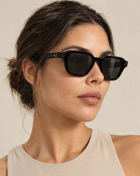 Mulher usando óculos de sol feminino quadrado preto modelo Bellagio LURVANI, em retrato de moda com enquadramento próximo.