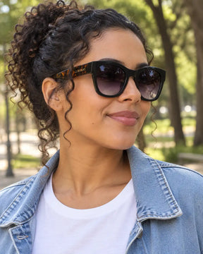 Mulher usando óculos de sol feminino quadrado preto modelo Ravenna LURVANI, em retrato de moda com enquadramento próximo.