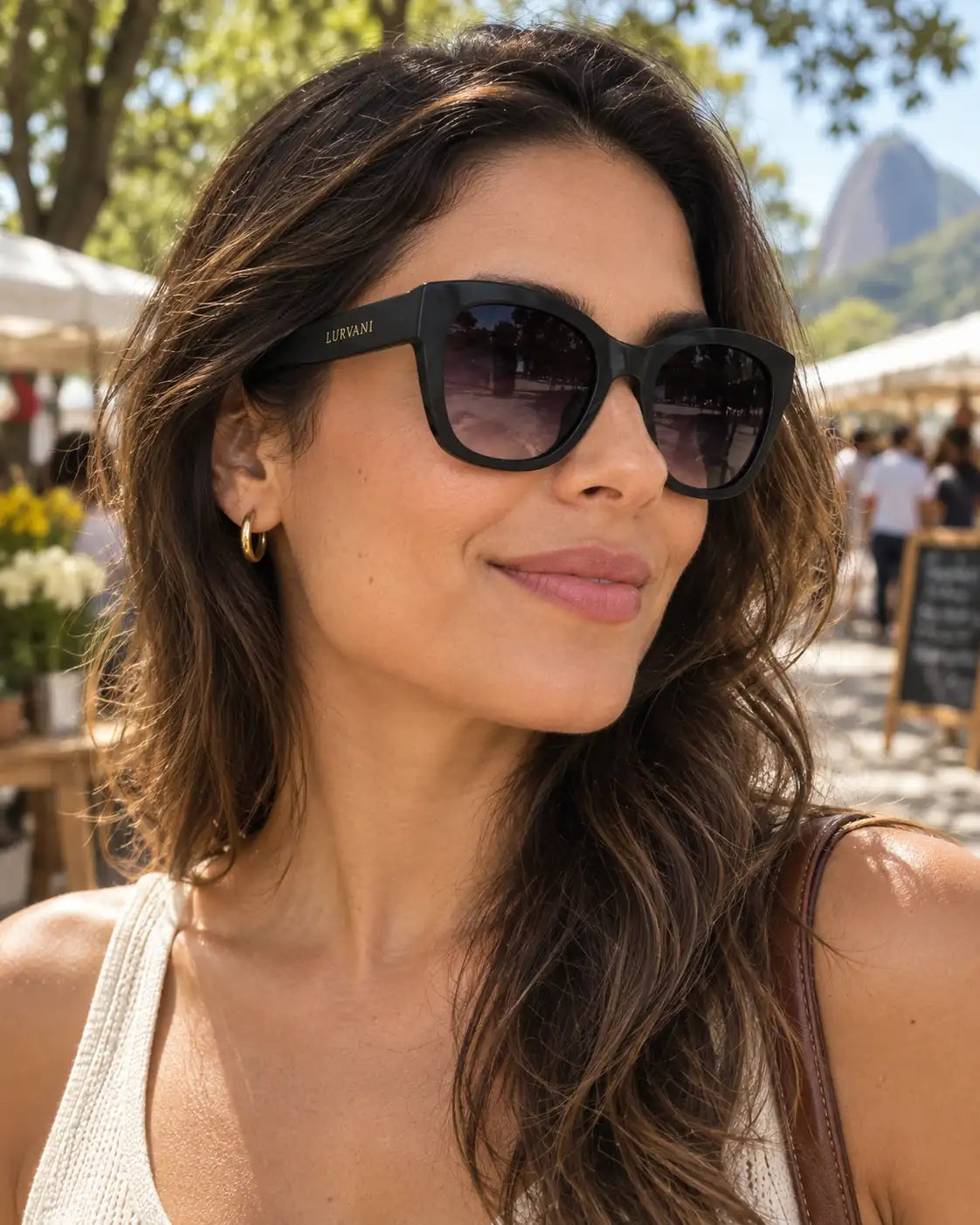 Mulher usando óculos de sol feminino quadrado preto modelo Violet LURVANI, em retrato de moda com enquadramento próximo.